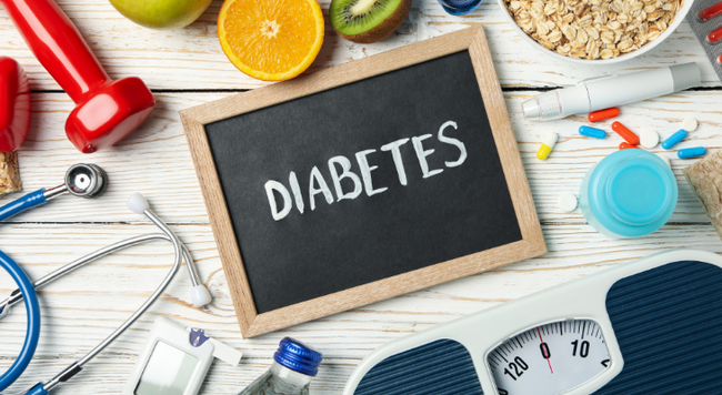 Image of chalkboard with the word Diabetes. Surrounding the chalkboard are the items: dumbbell, stethoscope, scale, medication, fruit, oatmeal, diabetic measuring device 